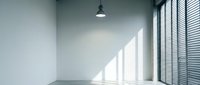 Empty modern office interior with large windows and venetian blinds casting natural light shadows on white walls and floor for business presentations.