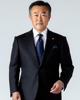 Confident mature Asian businessman in pinstripe suit and blue tie standing against white background, professional corporate portrait showing leadership and success.