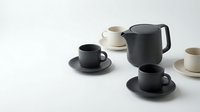 Modern minimalist ceramic coffee set with black teapot and cups on white background for kitchen design and hospitality branding projects.