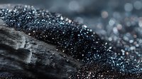 Macro view of dark crystalline mineral formation with sparkling blue and silver particles on rough stone surface. Geological specimen.