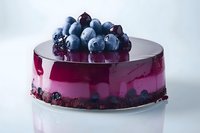Elegant blueberry mirror glaze cake topped with fresh berries on white background, showcasing modern patisserie art for food blogs and menus.