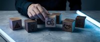 Business professional arranging wooden blocks with gear icons on desk representing teamwork, strategy, and corporate planning concepts for presentations.