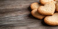 Heart shaped shortbread cookies on rustic wooden background with copy space. Fresh baked vanilla biscuits arranged in corner composition for Valentine's day.