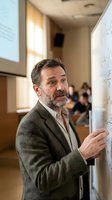 Middle-aged Caucasian professor with beard writing mathematical equations on whiteboard in modern university classroom during lecture.