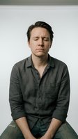 Stressed middle-aged Caucasian man with closed eyes showing mental fatigue and emotional exhaustion in casual green shirt against neutral background.