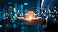 Businessman hand holding glowing house model with financial symbols and digital network connections against blurred city lights background for real estate investment.