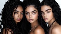 Three young diverse women with dramatic makeup and hairstyles including braids and curls pose together in artistic beauty portrait against dark background.