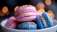 Colorful French macarons in pink and blue with gold sprinkles on white plate against blurred bokeh background, sweet dessert close up with soft focus effect.
