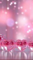Transparent pink glass hearts arranged in row against soft bokeh background, perfect for romantic greeting cards and Valentine designs.