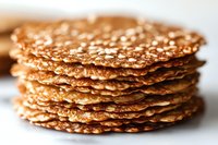 Stack of golden sesame seed crackers with crispy texture, healthy snacking and gourmet food concept for culinary designs and restaurant menus.
