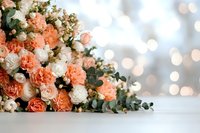 Romantic floral arrangement with coral and white roses, carnations, and eucalyptus leaves against soft bokeh background on white surface, creating dreamy atmosphere.
