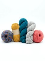 Colorful yarn balls and skeins in various textures and weights arranged on white background, ready for knitting, crochet, and craft projects.
