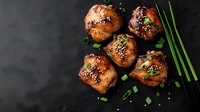 Glazed chicken thighs with sesame seeds and green onions on dark background, top view. Asian cuisine food photography for restaurant menu.