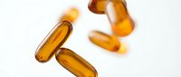 Golden omega-3 fish oil capsules scattered on white background for health and wellness supplement marketing materials.