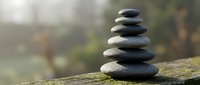 Balanced stack of smooth river stones creating zen meditation tower on weathered wooden surface with soft natural bokeh background for wellness and mindfulness concepts.