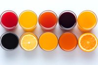 Fresh fruit juices and smoothies in glasses arranged in rows on white background, including orange, berry, and citrus varieties for healthy lifestyle concept.