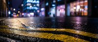 Rainy night city street with glowing bokeh lights reflecting on wet asphalt and yellow road markings, urban atmosphere after rain.