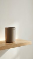 Minimalist ceramic storage jar with lid on wooden shelf against neutral beige wall. Modern kitchen organization and home decor styling for contemporary interiors.