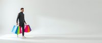 Man in dark business suit carrying colorful shopping bags on white background, representing retail therapy, consumer spending, and shopping lifestyle for commercial use.