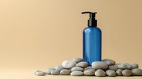 Blue cosmetic pump bottle on smooth pebbles against beige background, spa wellness concept for skincare and beauty products, minimal composition.