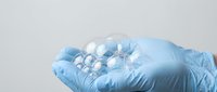 Medical professional in blue latex gloves holding white pharmaceutical pills or tablets for healthcare treatment and medication concept.