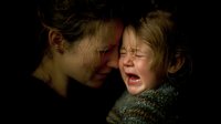 Young mother comforting crying child in dark setting, emotional moment of parental support during distress. Dramatic lighting highlights facial expressions.
