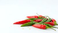 Fresh red and green chili peppers scattered on white background, spicy hot peppers for cooking and culinary use in kitchen recipes and food preparation.