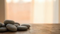 Zen spa stones arranged on wooden surface with soft natural window light creating peaceful meditation atmosphere for wellness and relaxation.