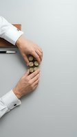 Two businessmen in white shirts arranging gold coins on gray surface, representing financial planning, investment strategy, wealth management and business collaboration.