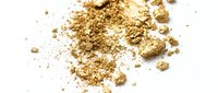 Scattered gold glitter and metallic particles on white background, suitable for luxury branding, cosmetics, celebrations, and festive design projects.