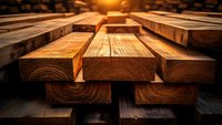 Stacked wooden planks and lumber materials illuminated by warm sunset light, showcasing natural wood grain texture and construction elements.