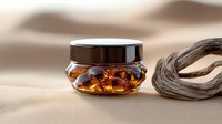 Luxury amber-colored cosmetic cream in decorative glass jar with black lid on beige silk background, elegant skincare product photography for beauty industry.