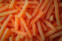 Fresh cut raw carrot sticks in bright orange color arranged in chaotic pattern, macro food photography showing texture and natural vegetable detail.