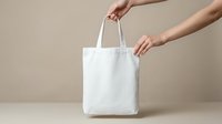 White cotton tote bag mockup held by female hands on neutral beige background for branding and design presentation.