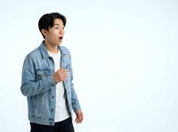 Surprised young Asian man wearing blue denim jacket and white shirt, isolated on white background, suitable for advertising, marketing, and lifestyle design projects.