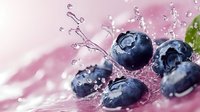 Fresh ripe blueberries with water splash and droplets on pink background, macro shot showing juicy berries in dynamic motion with liquid spray.