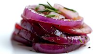 Fresh sliced red onion rings seasoned with herbs and spices on white background, macro shot showing texture and layers with selective focus.