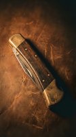 Vintage folding pocket knife with wooden handle on worn leather surface in warm atmospheric lighting for outdoor adventure concepts.
