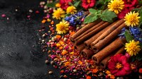 Aromatic cinnamon sticks with vibrant yellow and red flowers, scattered spices and dried petals on dark rustic background, creating festive culinary composition.