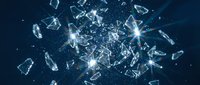 Shattered glass fragments exploding with bright light rays on dark blue background for dramatic impact designs and creative projects.