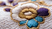 Colorful floral embroidery with gold thread accents on fabric showcasing traditional needlework craftsmanship for textile and fashion design projects.