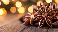 Star anise pods on rustic wooden surface with warm golden bokeh lights in background creating cozy festive atmosphere for winter holiday season.