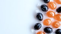 Orange and black wrapped hard candies arranged on white background, perfect for Halloween season treats or festive candy displays.