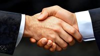 Professional business handshake between two male executives in suits symbolizing partnership agreement, trust, and successful deal closing on dark background.