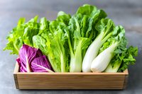 Fresh green lettuce and purple radicchio in wooden box on dark background, healthy organic vegetables for salad and cooking. Farm produce.