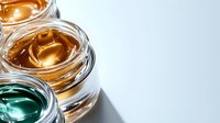 Luxurious cosmetic creams in glass jars with golden and emerald textures on white background. Professional skincare and beauty products arranged in minimal style.