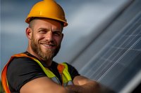 Smiling bearded Caucasian male solar panel installer in safety helmet and reflective vest working with photovoltaic modules during sunny day.