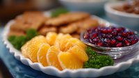 Fresh orange segments and cranberries served on white scalloped plate with garnish, healthy breakfast ingredients and natural vitamin C sources for immune system.