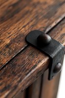 Close-up of rustic black metal latch on weathered wooden surface showing vintage craftsmanship and textural details, highlighting contrast between materials.