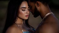 Intimate portrait of mixed race couple in romantic embrace against dark background. Woman with long dark hair and man with beard share tender moment.